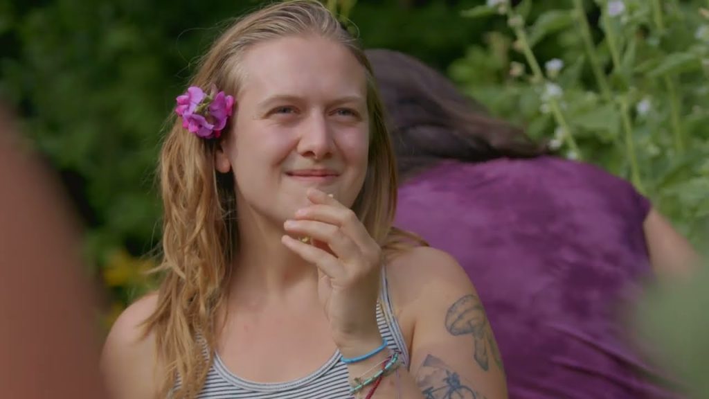 Yana Retreat / Sarana Institute mini documentary placeholder image woman with pink flower in hair stands in a forest